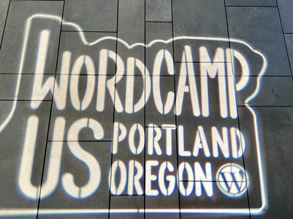 The WordCamp US Portland, Oregon logo projected onto the pavement